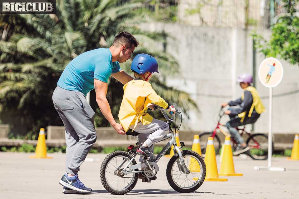 Un niño de 2 años aprende a andar en bicicleta de equilibrio en la  carretera de la aldea.